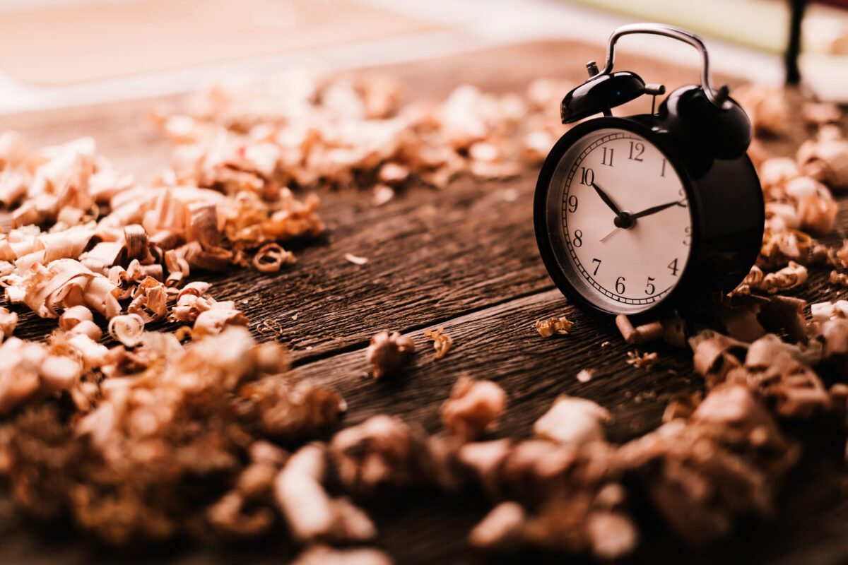 black alarm clock with wood sawdust on wooden floor